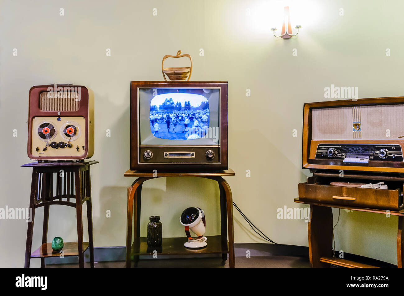 Carrete a otro jugador, televisor en blanco y negro y un viejo radio de onda media y larga en un salón de la década de 1950. Foto de stock