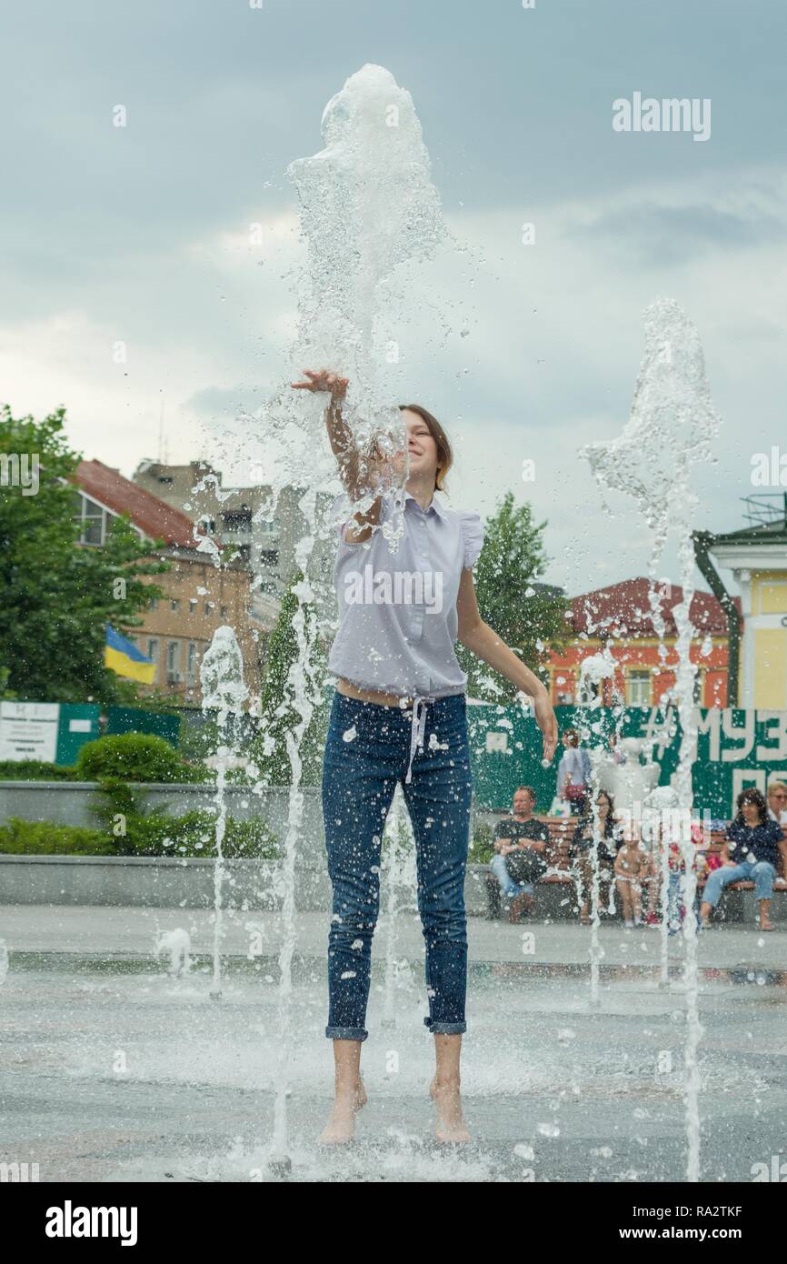 Kiev UA 19/07/-2018,. Alegre adolescente en la ciudad Trevi, chica en mojada es divertirse y disfrutar el fresco en verano, el agua de la ciudad de fondo Fotografía
