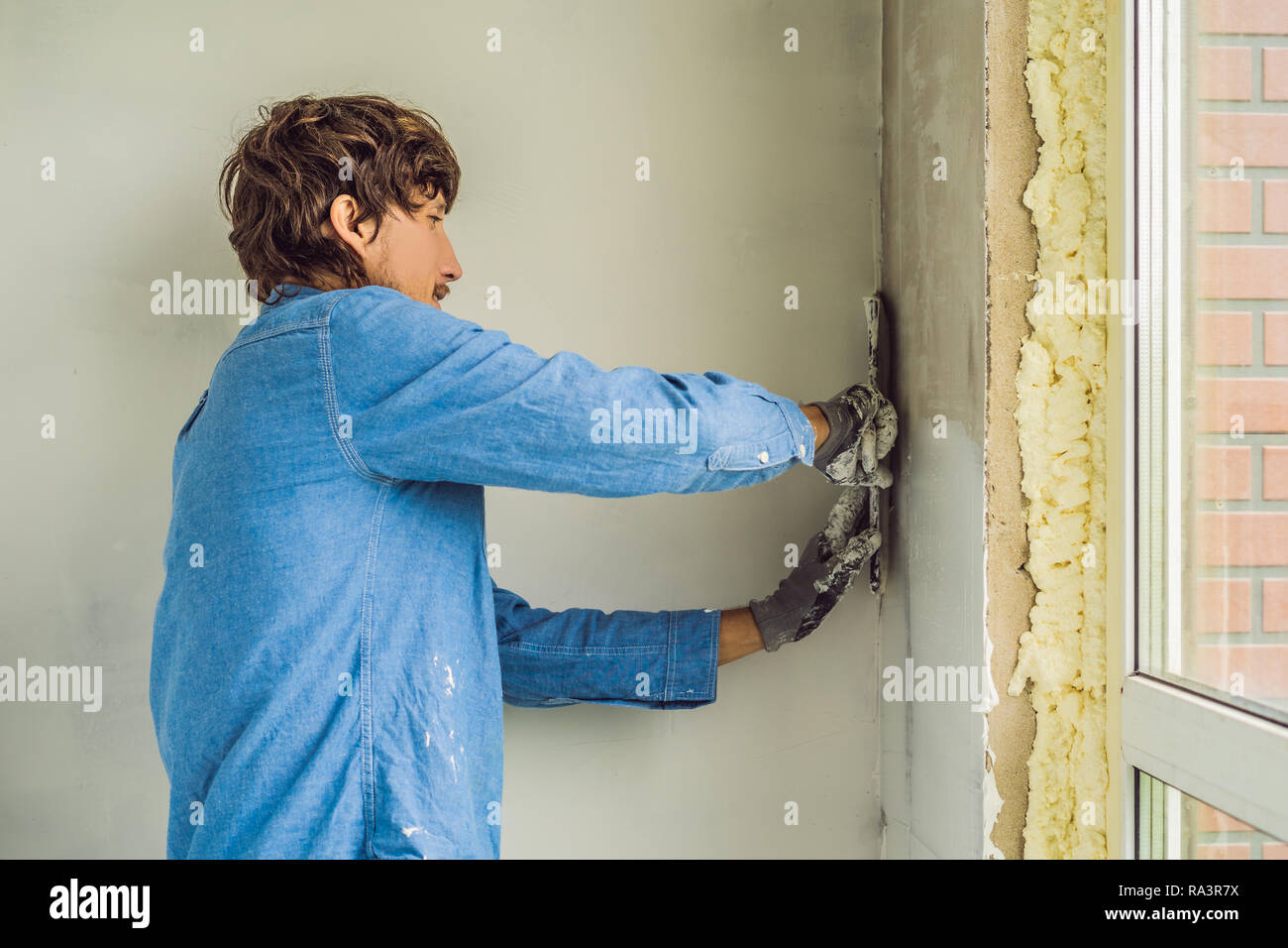 Master está aplicando masilla blanca sobre una pared y manchas por
