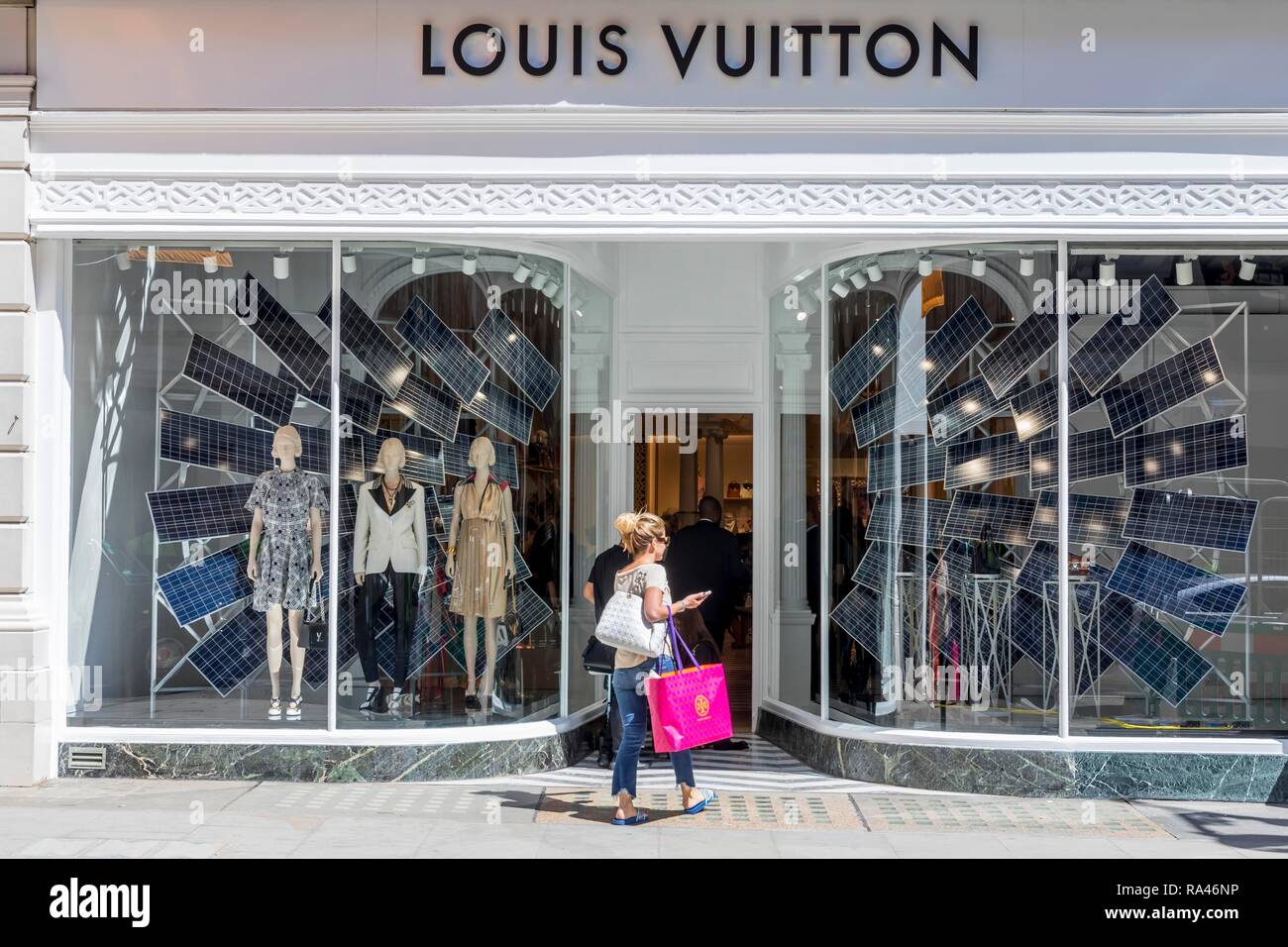 Los transeúntes delante del escaparate de la tienda de moda Louis Vuitton, Londres, Reino Unido. Foto de stock