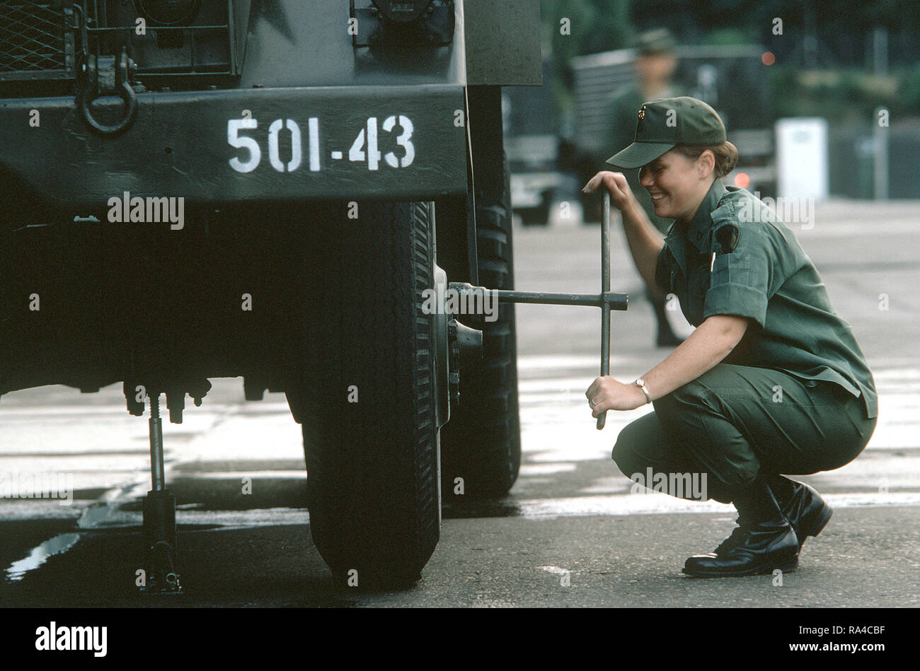 1974 - Una mujer soldado del ejército estadounidense se aprieta un tornillo de rueda en un vehículo militar. Foto de stock