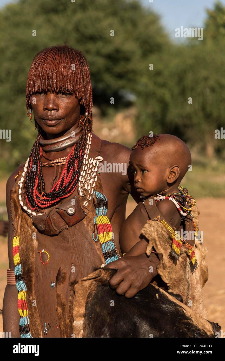 Una mujer con un bebé de la tribu Hamer en traje tradicional, Turmi, Nación Meridional, región de Etiopía Foto de stock