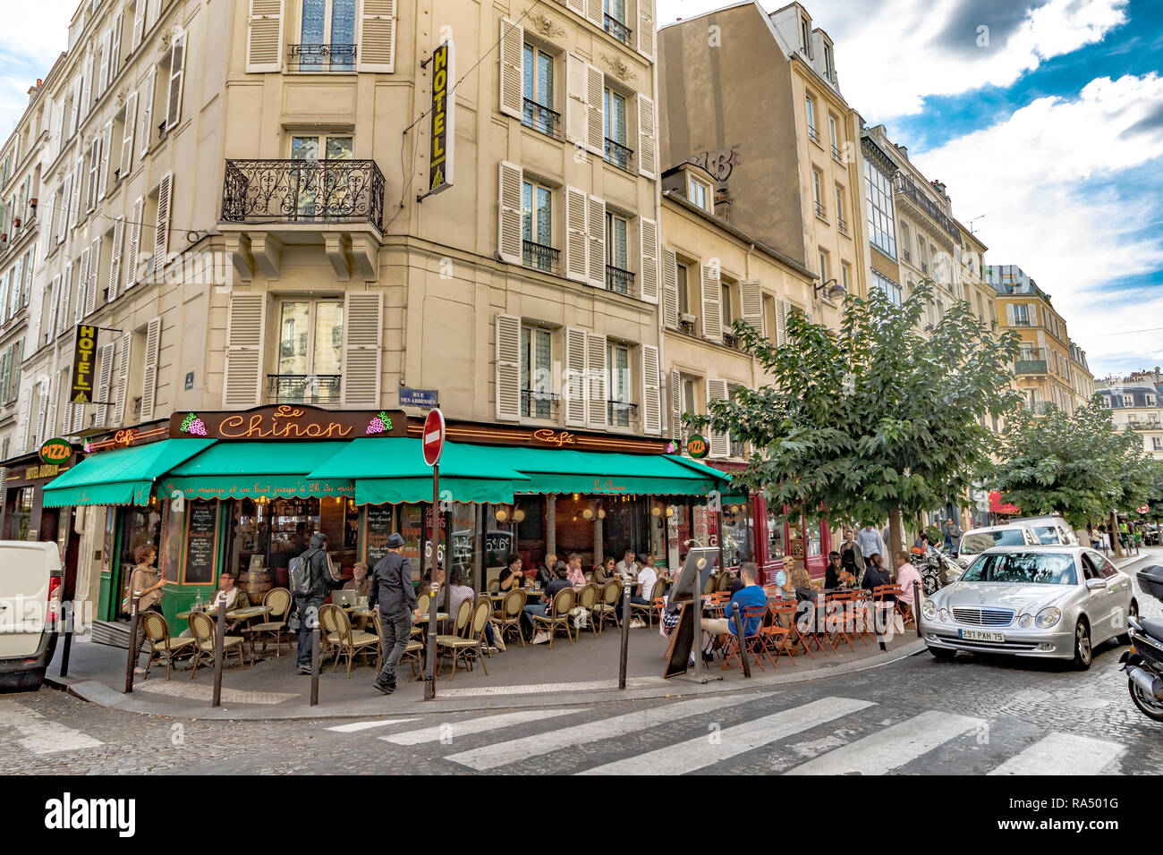 La gente comiendo fuera en el pavimento de tablas en Le Chinon restaurante y cafetería, Rue des Abbesses, Paris Foto de stock