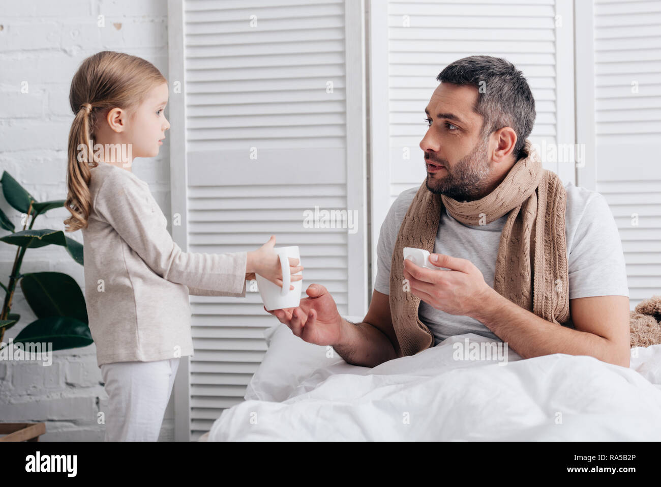 Vista lateral de la adorable hija dando taza de té para papá enfermo en  dormitorio Fotografía de stock - Alamy