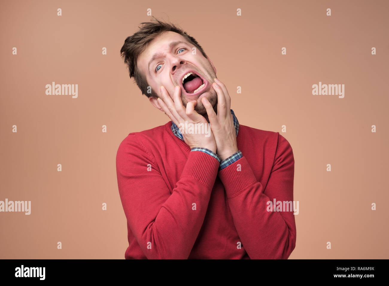 Los jóvenes europeos hombre de sweater rojo llanto de dolor anf aflicción  sobre fondo marrón Fotografía de stock - Alamy