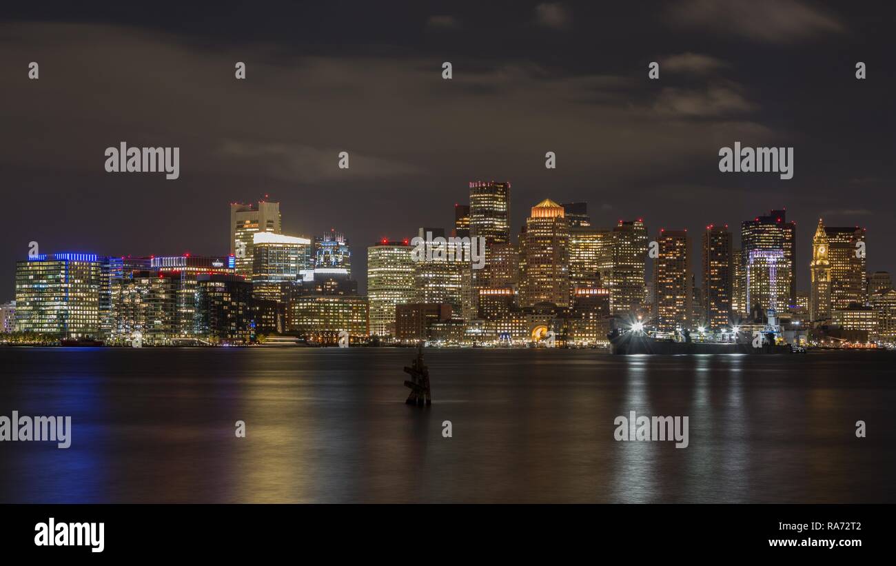 Vistas del perfil de la ciudad de Boston en la noche, rascacielos, delante del canal principal de Boston, Boston, Massachusetts, EE.UU. Foto de stock