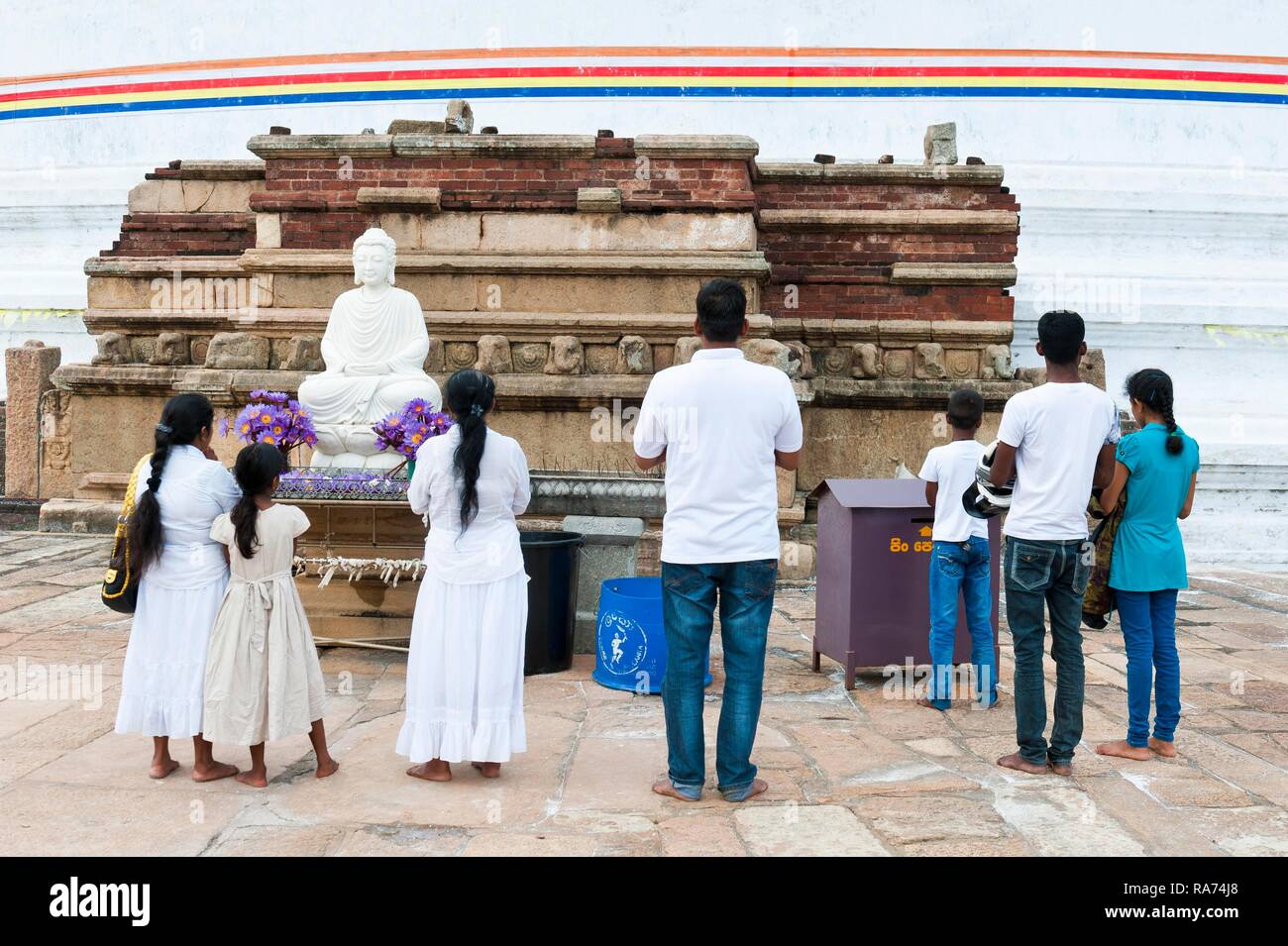 El cingalés familia creyente delante de la estatua de Buda en el santuario, Mirisavatiya-Dagoba, Anuradhapura, norte y centro de la provincia Foto de stock