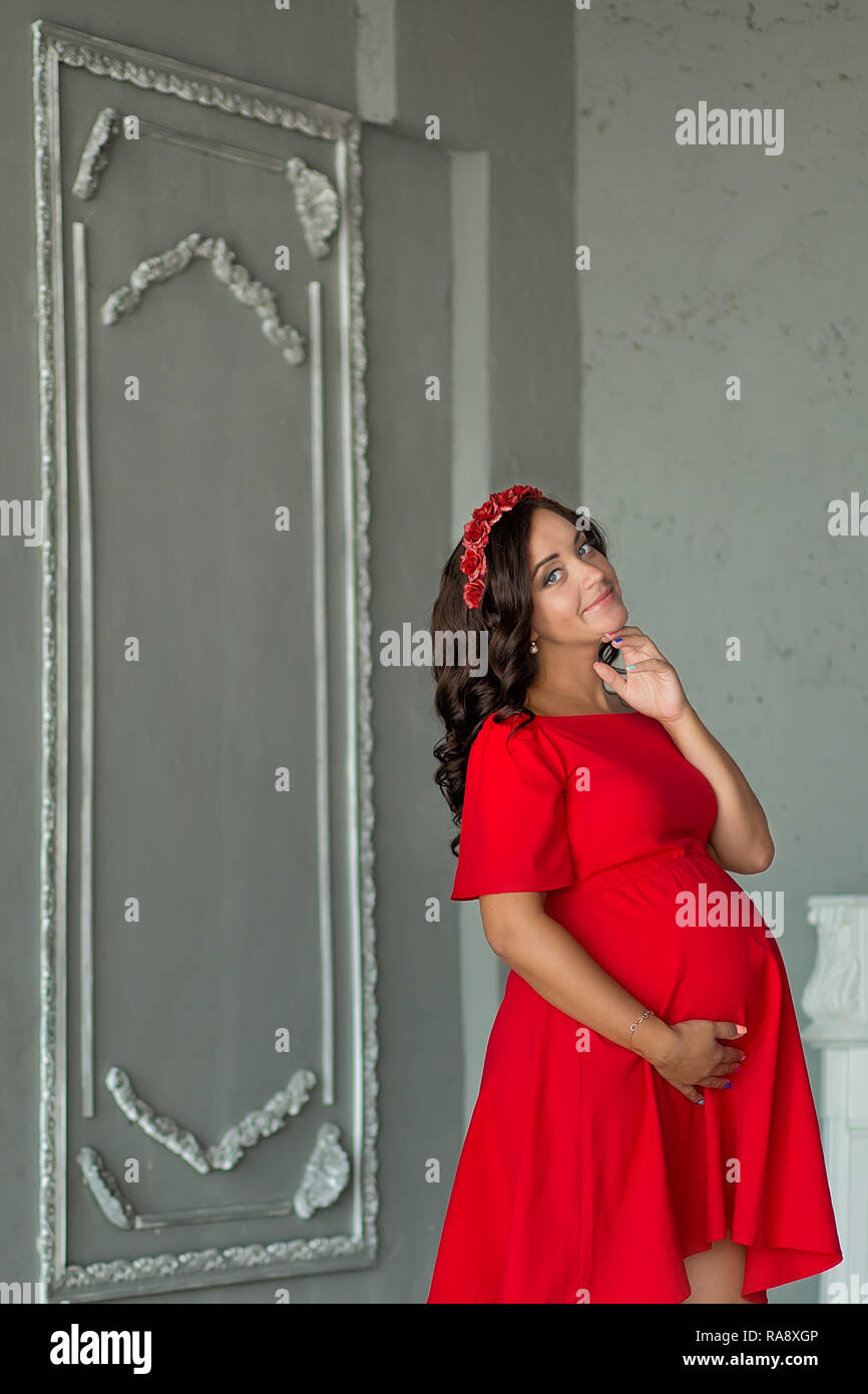 Impresionante joven morenita mujer embarazada en vestido rojo Bonito  estudio de corte Fotografía de stock - Alamy