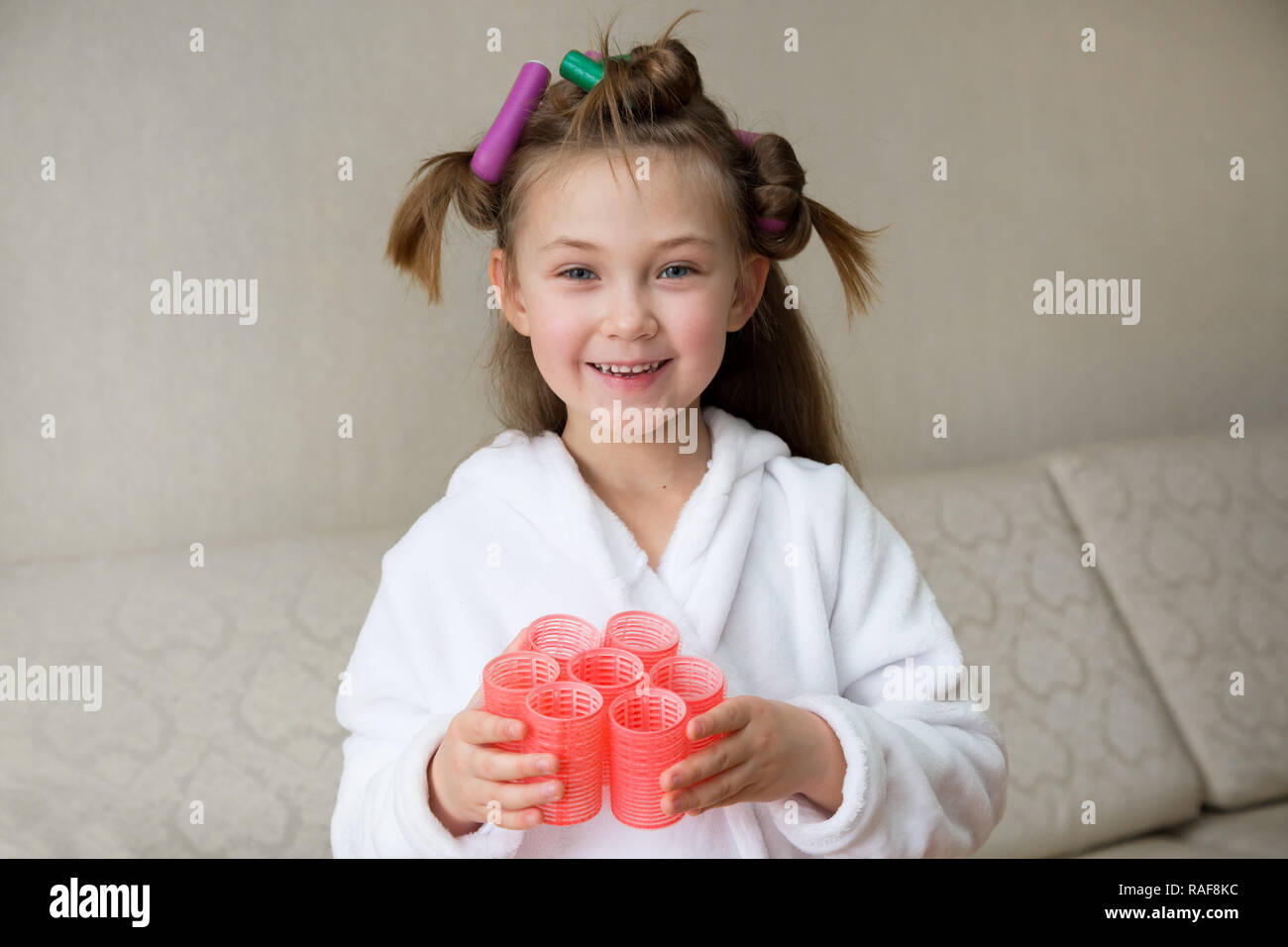 Pequeña niña en una bata blanca con horquillas en el cabello de su cabeza  Fotografía de stock - Alamy