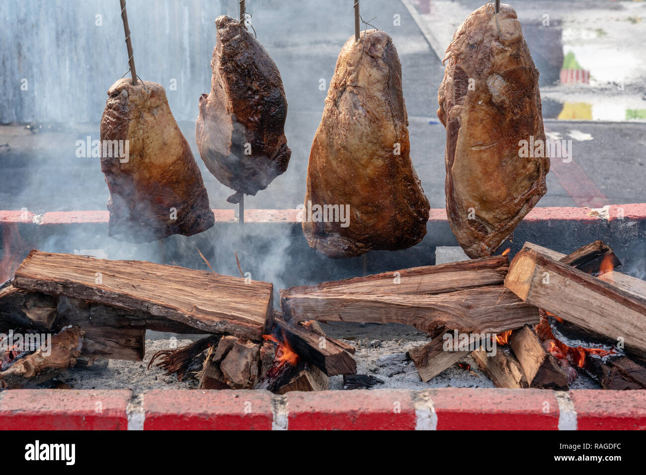 Cuatro grandes trozos de carne en un asador cocinar sobre un fuego de  madera abierto con humo y llamas Fotografía de stock - Alamy