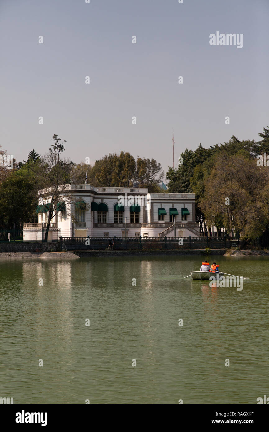 Una madre y sus dos hijos visten un chaleco de espuma cada como son paseos en bote en frente de la Casa del Lago artificial en el lago de Chapultepec en Mex Foto de stock