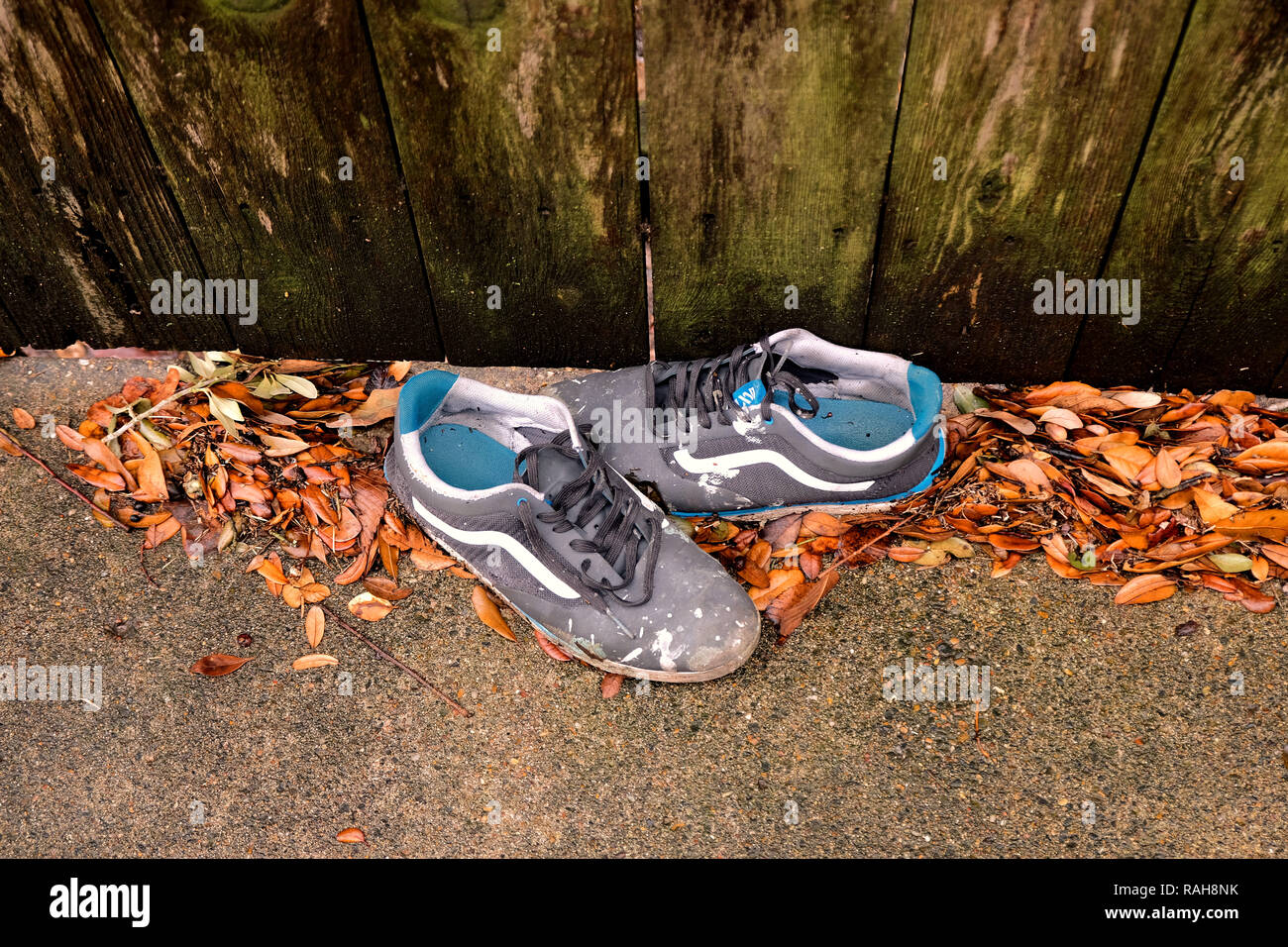Par de zapatillas viejas, rodeado de hojas secas en la base de una valla de  madera desgastada; pintura blanca gotea sobre los zapatos Fotografía de  stock - Alamy