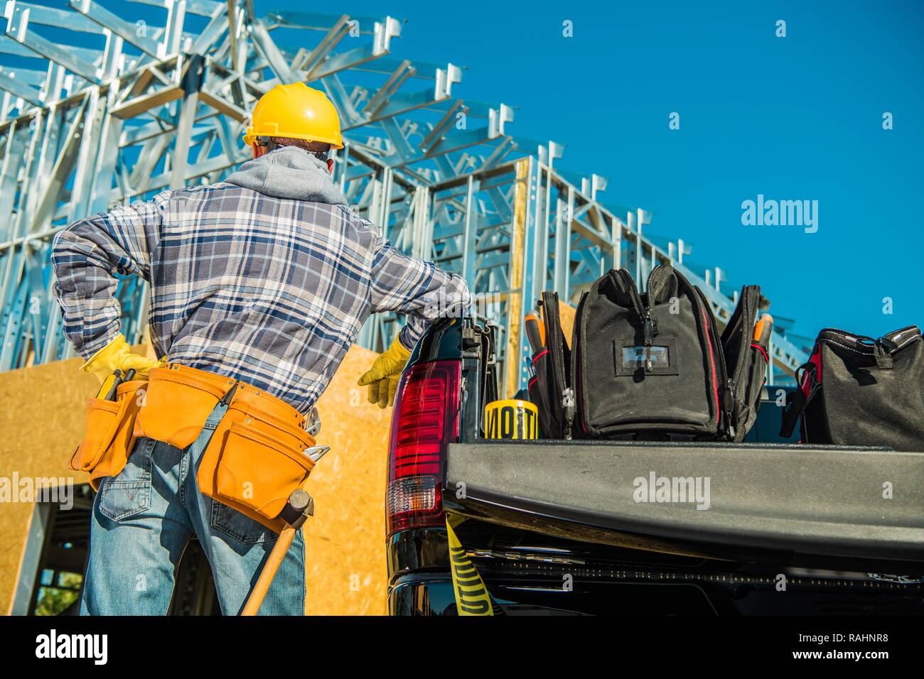 Trabajo de contratistas de la construcción. Trabajador caucásico llevar casco de seguridad amarillo en la parte delantera del edificio recientemente desarrollado. Foto de stock