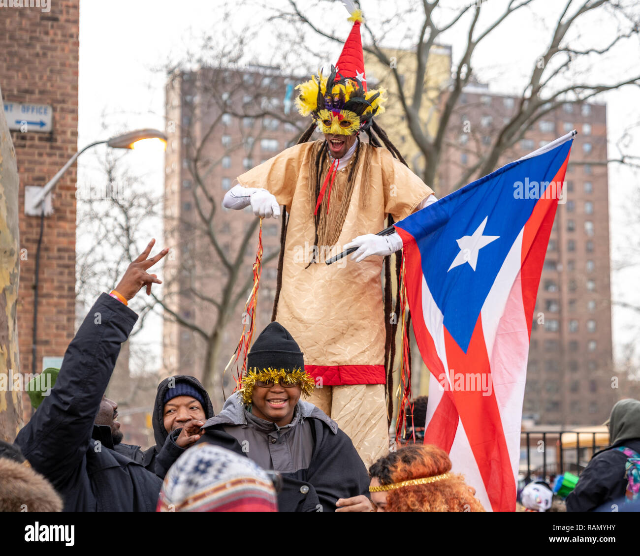 Guiño comerciante ambiente Nueva York, Estados Unidos. El 4 de enero de 2019. Un intérprete en zancos  sostiene una bandera de Puerto Rico como él interactúa con el público que  asiste a la 42ª Jornada