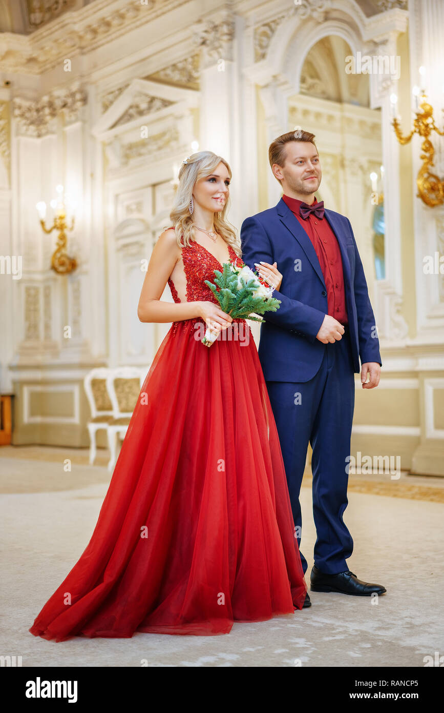 Una mujer hermosa en un vestido rojo destaca con un hombre, la novia y el  novio, felices recién casados Fotografía de stock - Alamy