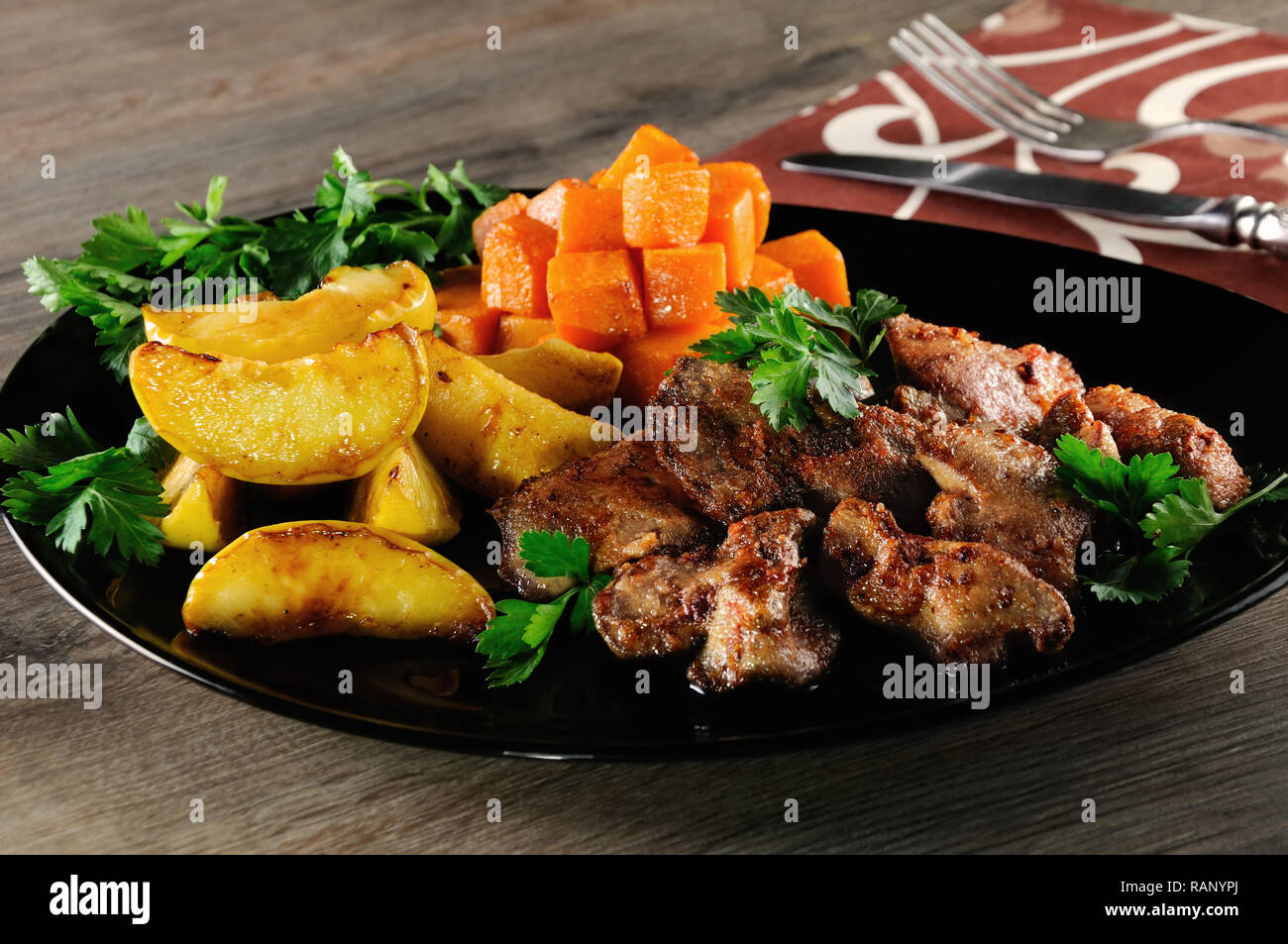 El hígado de pollo frito con guarnición de verduras, calabaza cocida y Apple. Foto de stock