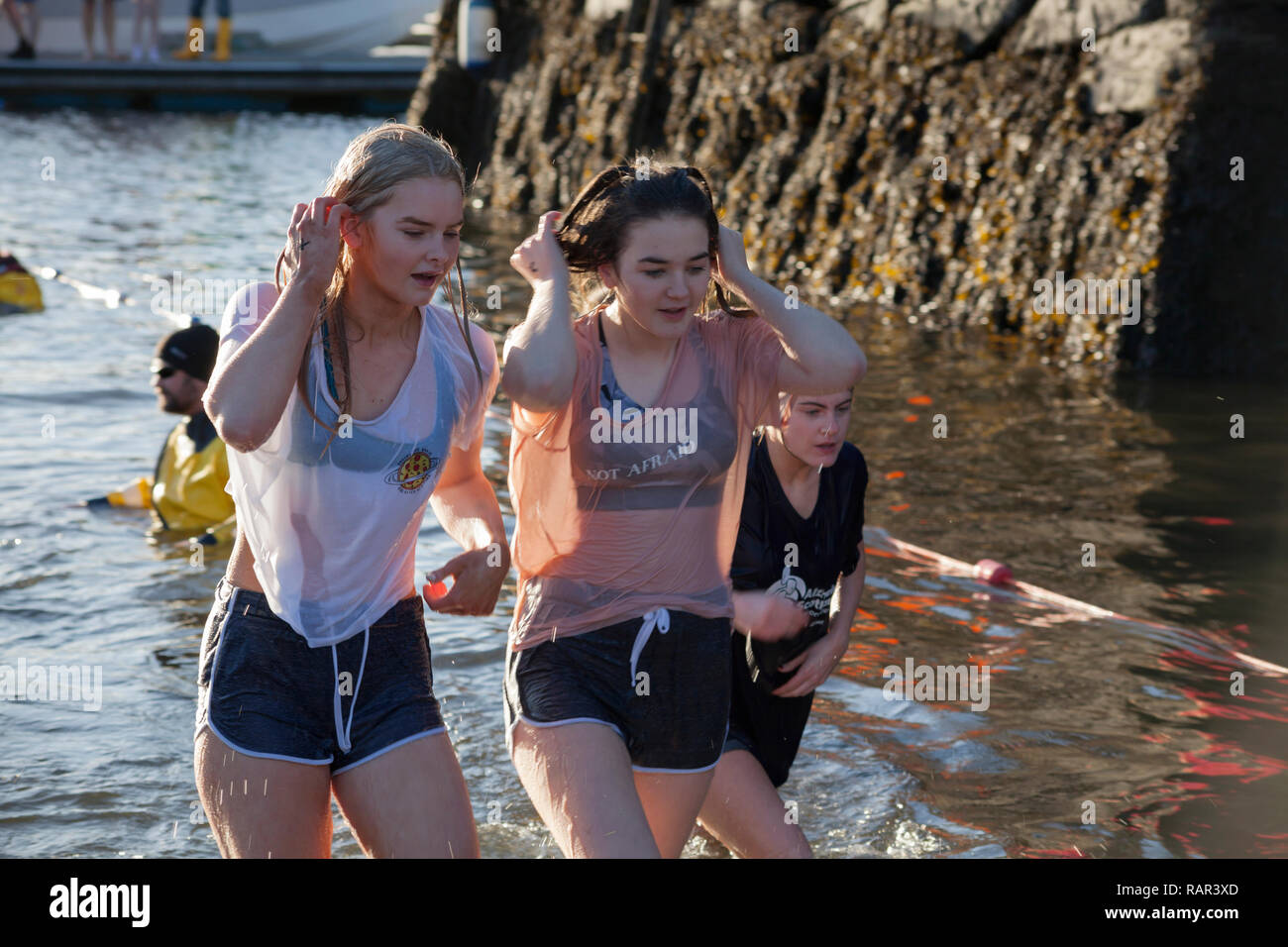 Dos niñas que emergen de las aguas en el día de Año Nuevo nadar en Rhu Marina, Escocia Foto de stock
