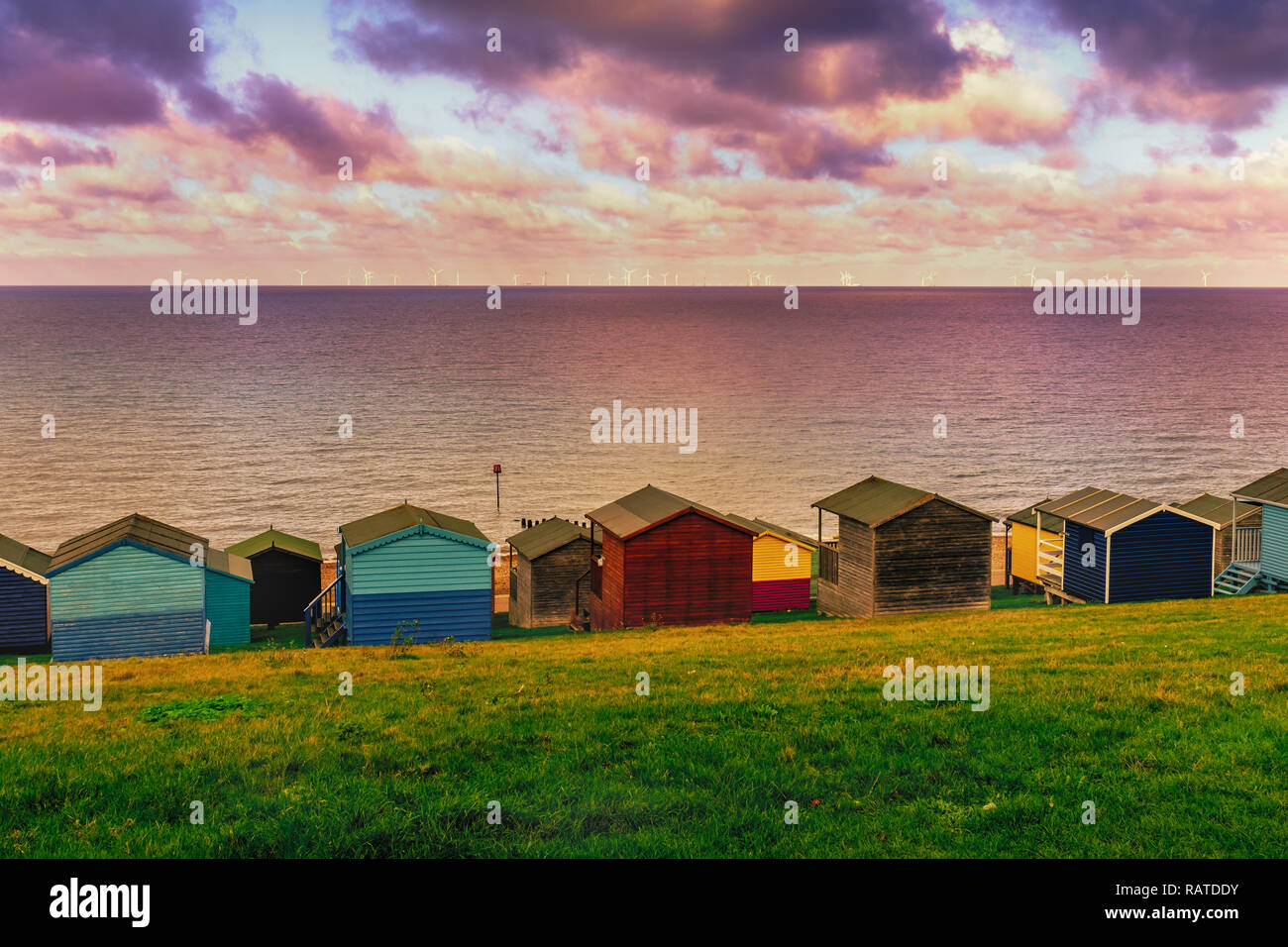 Moody nublado crear parches de sol entre las nubes en el mar en Tankerton, de Whitstable, en Kent. Filas de cabañas de playa de madera de la línea Foto de stock