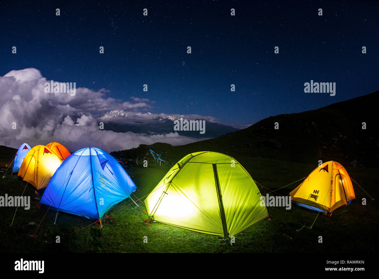 Una fila de tiendas de campaña durante la noche sobre Khalia arriba por encima de la ciudad de Munsyari en Uttarakhand, al norte de la India, en los Himalayas. La Panchchuli picos en la distancia. Foto de stock