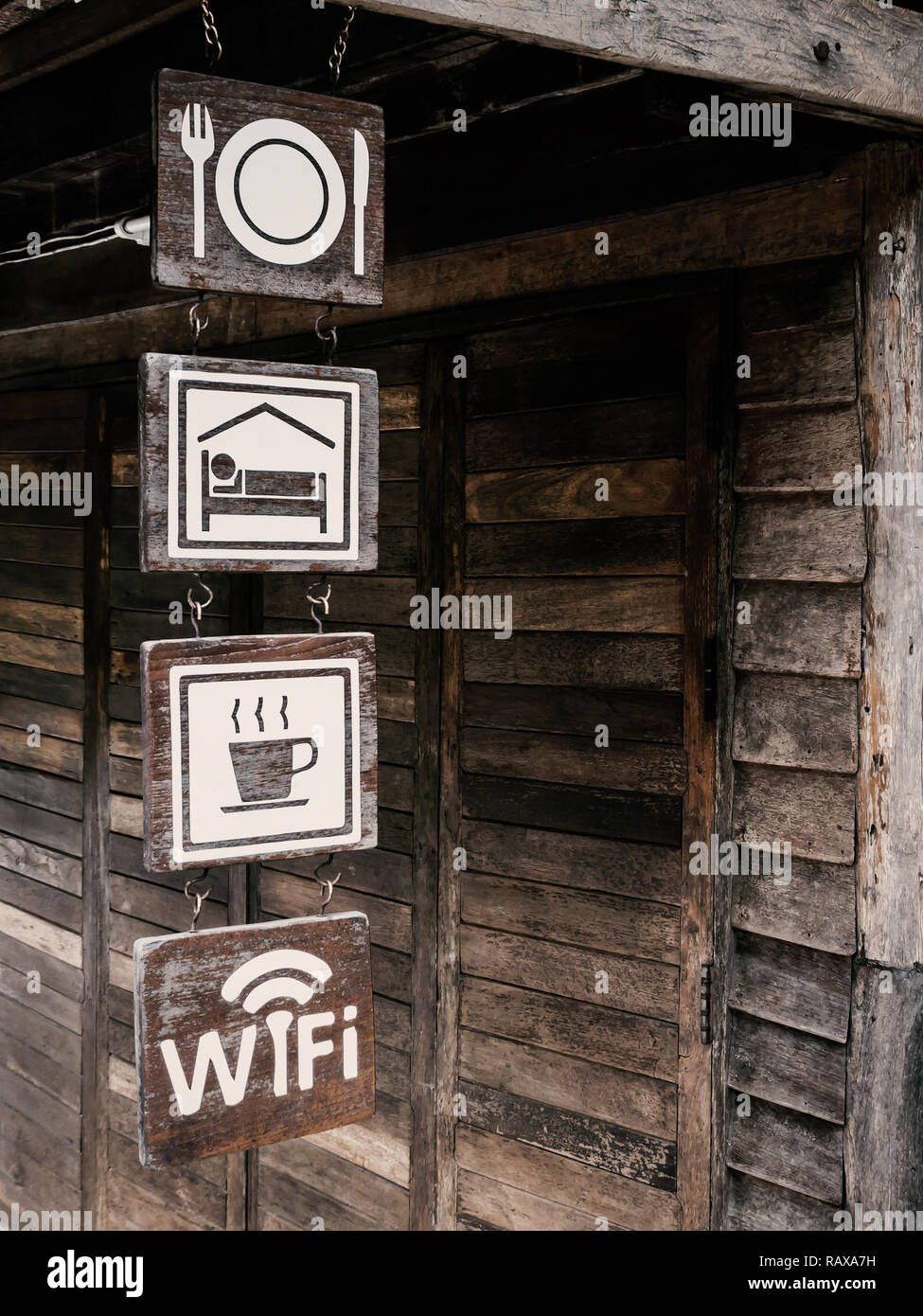 Comida, habitación, bebida y Wi-Fi gratuito cartel de madera en vintage pared de madera fondo de homestay en Tailandia, tonos oscuros Foto de stock
