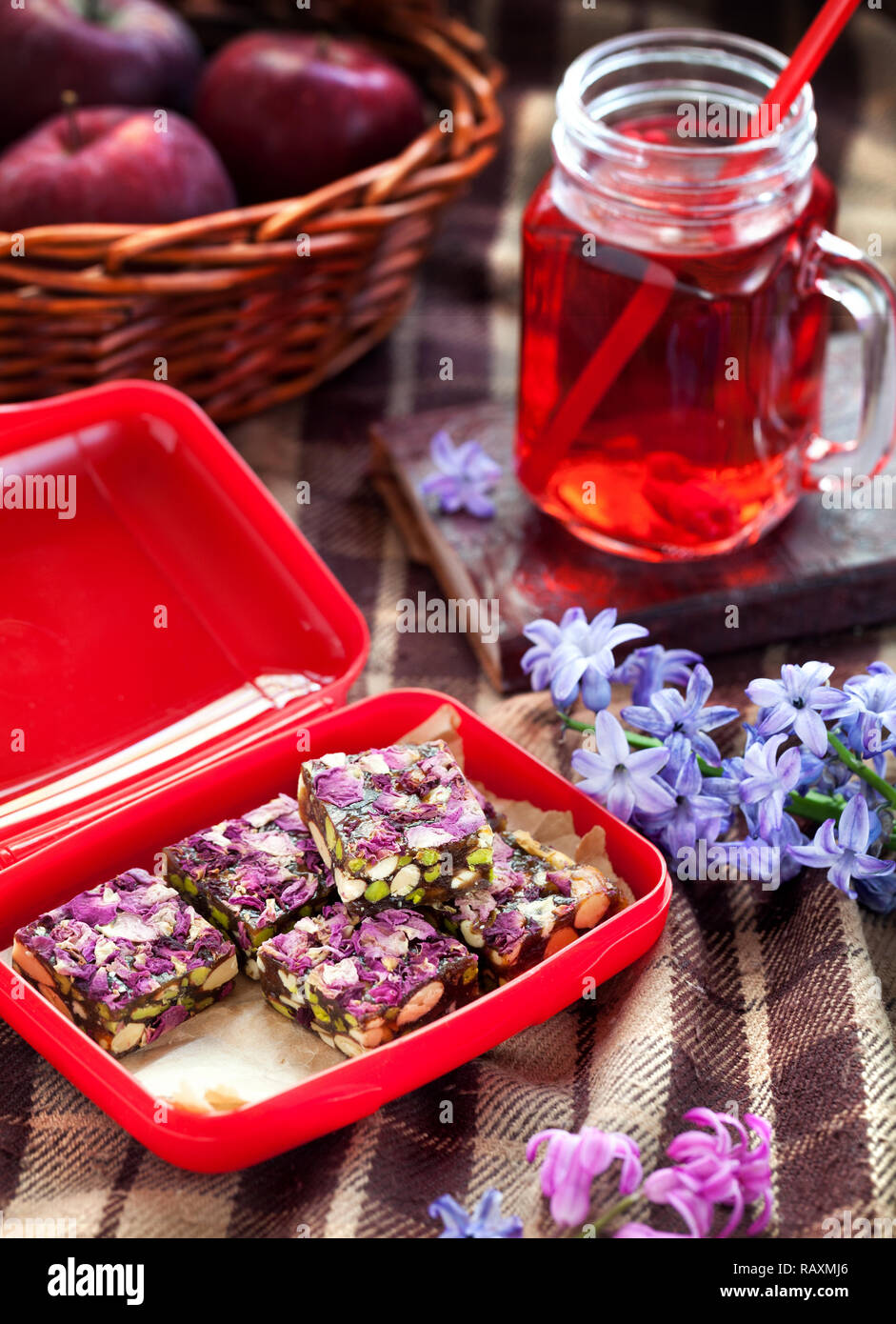 Picnic con dulces, bebidas de frambuesa y manzanas en la manta en el fin de semana de primavera Foto de stock