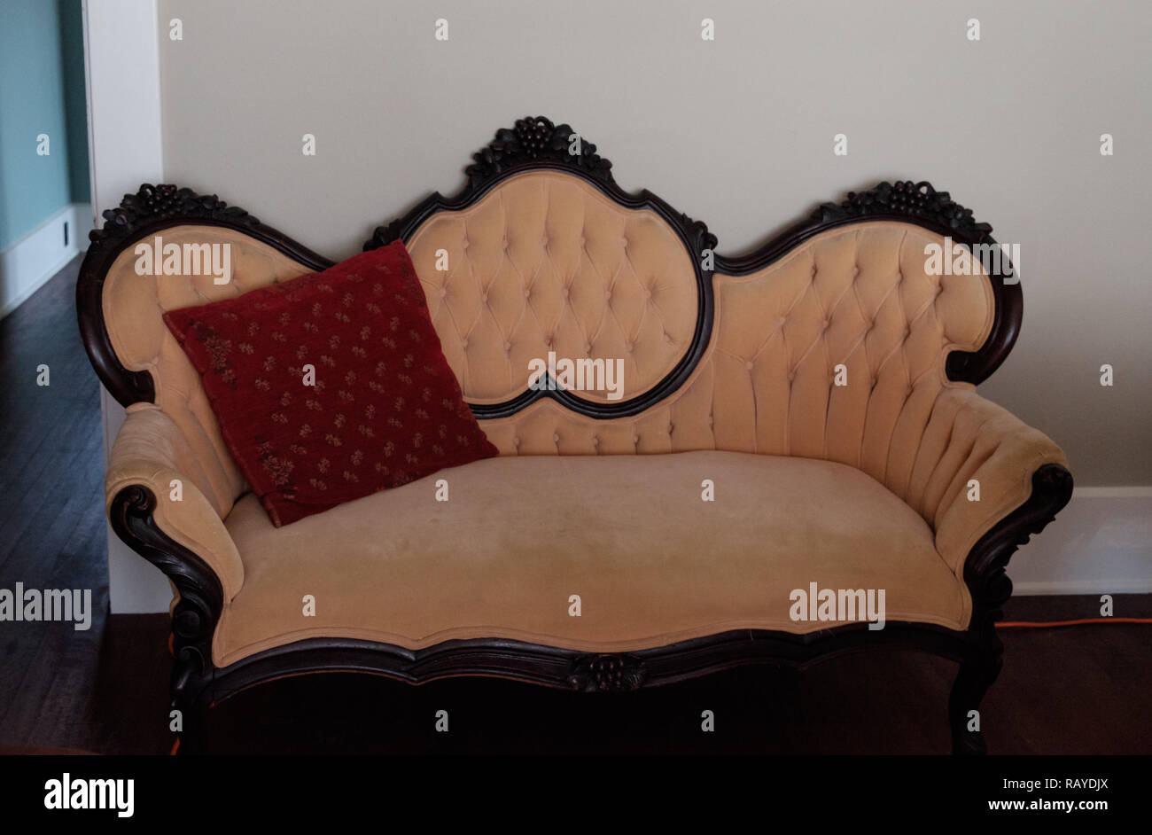 Antiguo sofá tapizado con revestimiento de madera marrón y rojo lanzan almohada. Interior de la histórica Casa tejano, Castaños Square Historic Village, McKinney, Texas. Foto de stock