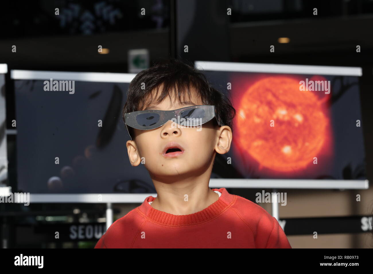 Seúl, Corea del Sur. 06Th ene, 2019. Eclipse solar parcial de un niño observa un eclipse solar parcial con unas gafas especiales en el observatorio de Lotte World Tower, en el sur de Seúl el 6 de enero de 2019. Crédito: Yonhap/Newcom/Alamy Live News Foto de stock
