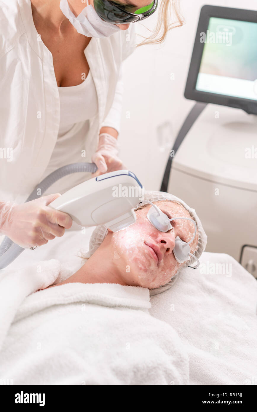 Anti acné fototerapia con equipo profesional. Hermosa mujer de salón de  belleza durante el procedimiento de rejuvenecimiento de la foto.  Tratamiento de la piel facial con láser en la clínica de estética.