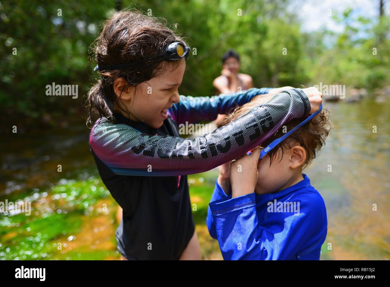Una madre cuida a sus hijos nadar en un arroyo, Alligator Creek, Townsville, Queensland, Australia Foto de stock