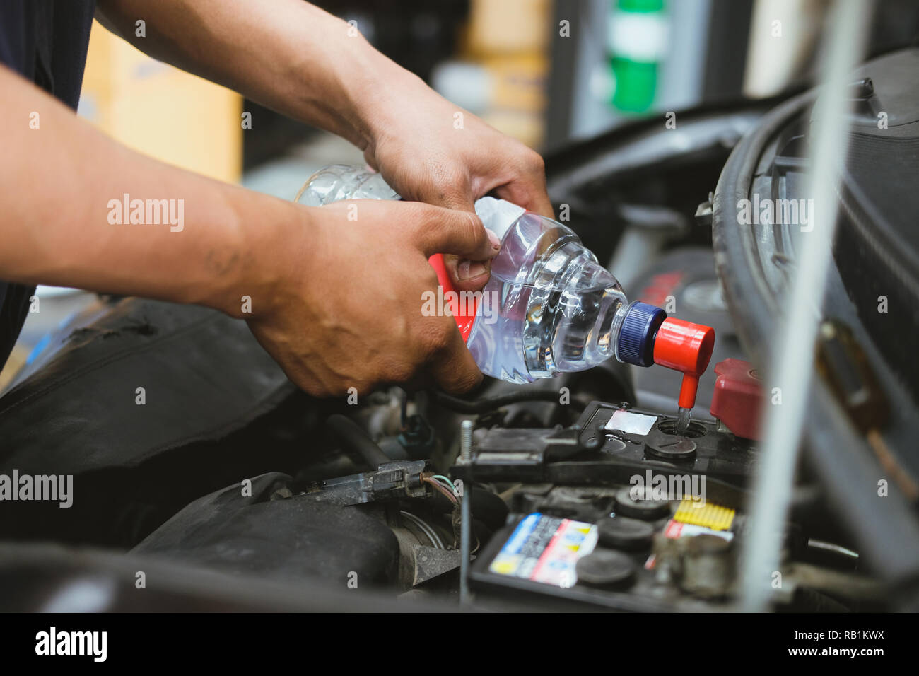 Mechanic vertiendo agua destilada para llenar la batería del automóvil en  reparación de automóviles garaje Fotografía de stock - Alamy