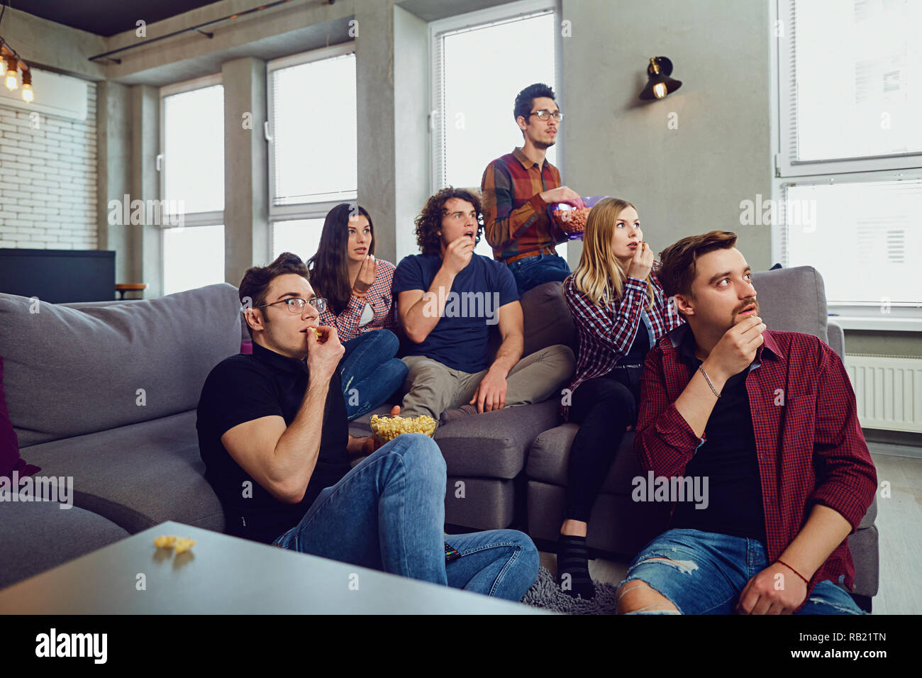 Un grupo de amigos se divierten viendo la televisión en la habitación. Foto de stock