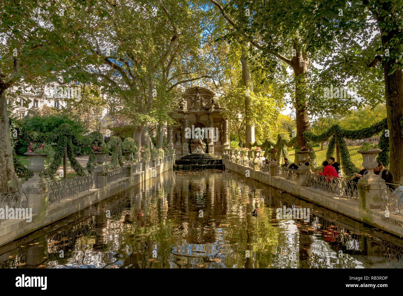 Gente sentada junto al estanque en la Fuente de Medici o Fontaine de Medicis, una fuente monumental, en un día de verano en el Jardín de Luxemburgo, París Foto de stock
