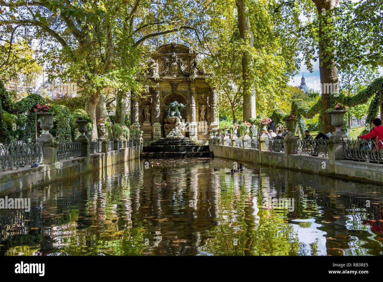 Gente sentada junto al estanque en la Fuente de Medici o Fontaine de Medicis, una fuente monumental, en un día de verano en el Jardín de Luxemburgo, París Foto de stock