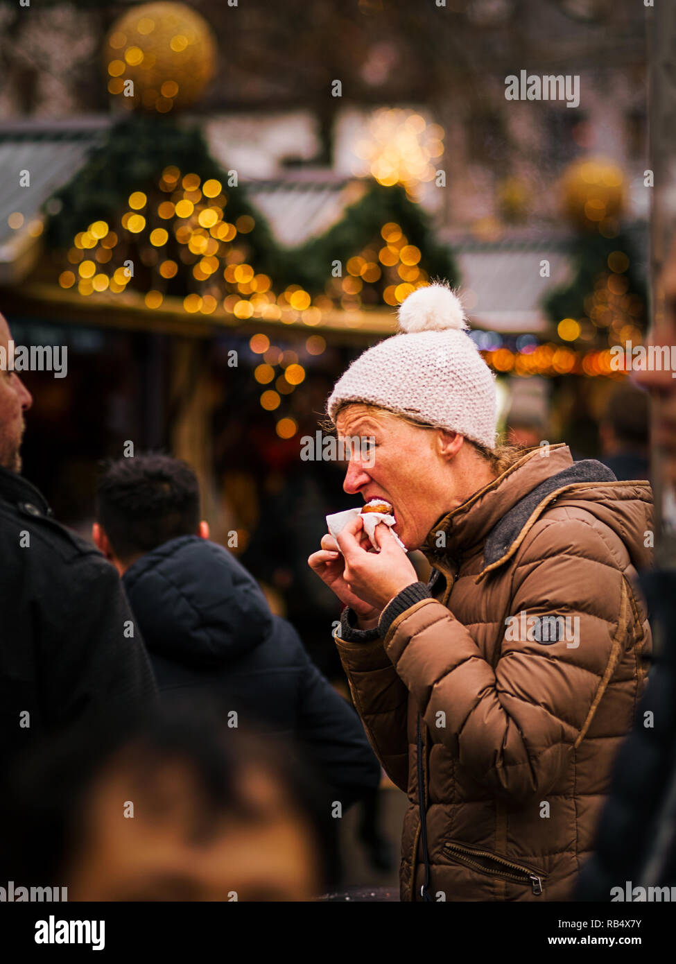 El 25 de diciembre de 2018- Amberes Bélgica: Cierre con teleobjetivo de mujer vistiendo ropa de invierno marrón con sombrero de lana de color blanco en una feria de Navidad comer Foto de stock