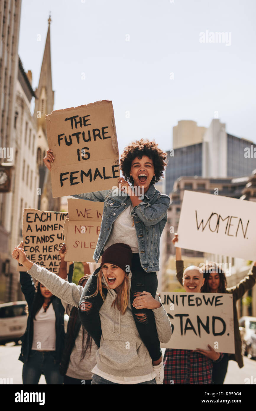 Grupo de jóvenes activista protestando con letreros en la carretera. Las mujeres disfrutan durante una manifestación en la carretera. Foto de stock