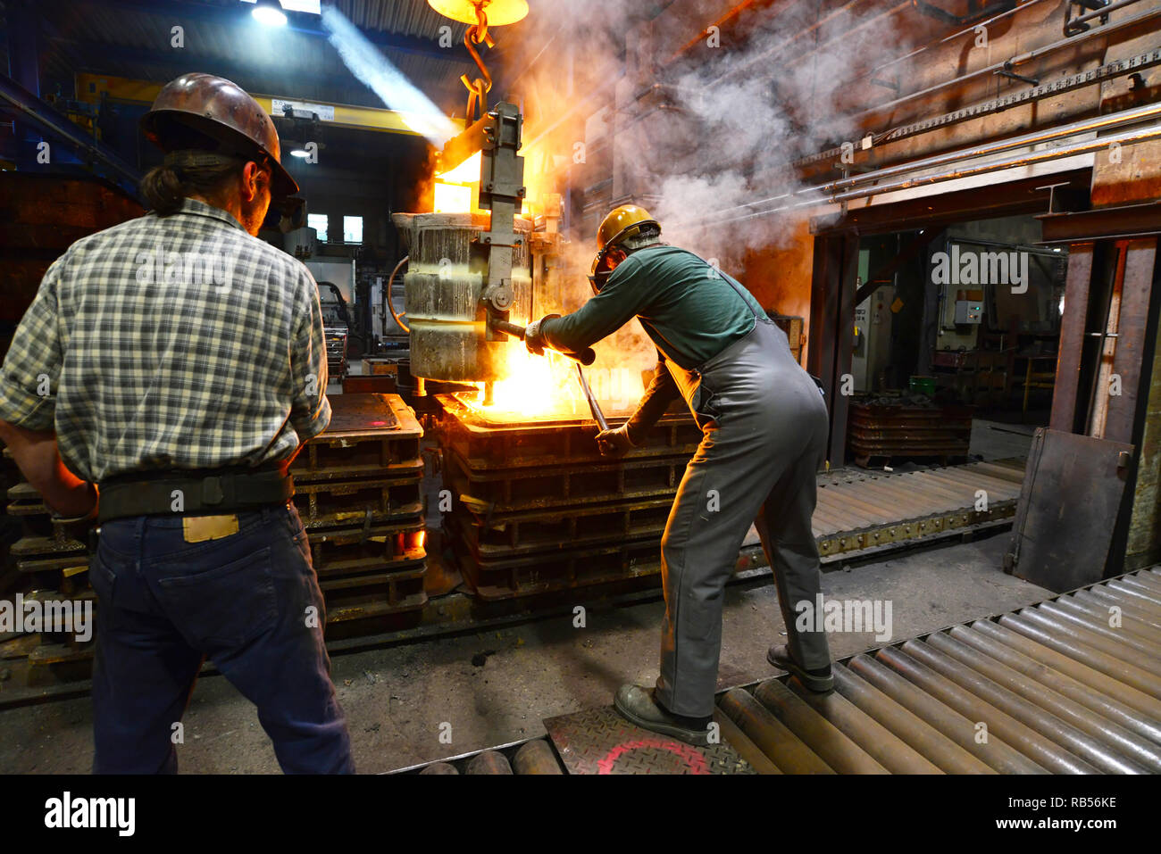 Los trabajadores en una pieza de metal de fundición - Seguridad en el trabajo y el trabajo en equipo Foto de stock