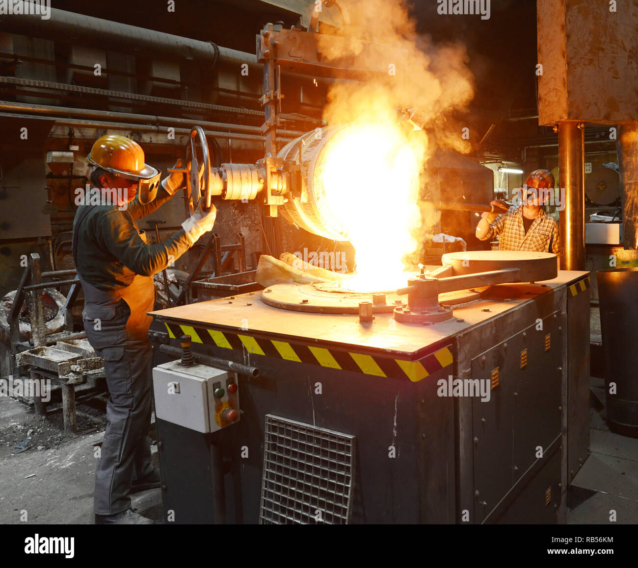 Los trabajadores en una pieza de metal de fundición - Seguridad en el trabajo y el trabajo en equipo Foto de stock