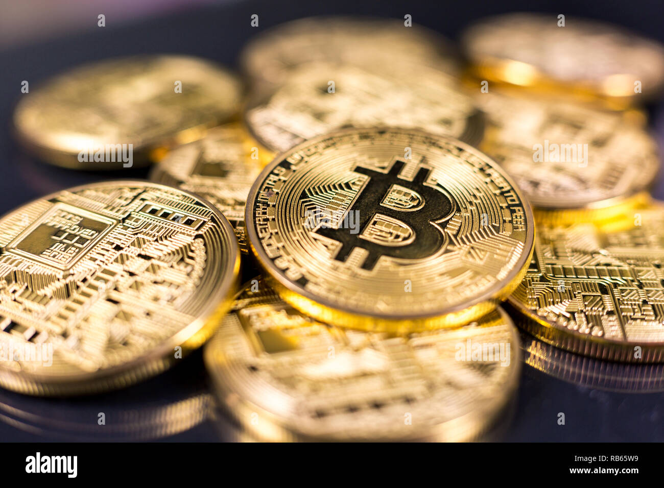 Pila de bitcoins acostado sobre la superficie oscura brillante Foto de stock
