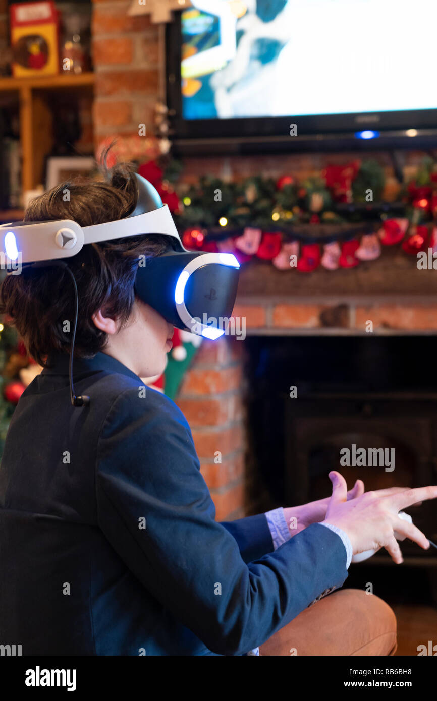 Un niño de 8 años que llevaba un casco de realidad virtual de Sony y jugando a un juego de ordenador de realidad virtual Foto de stock