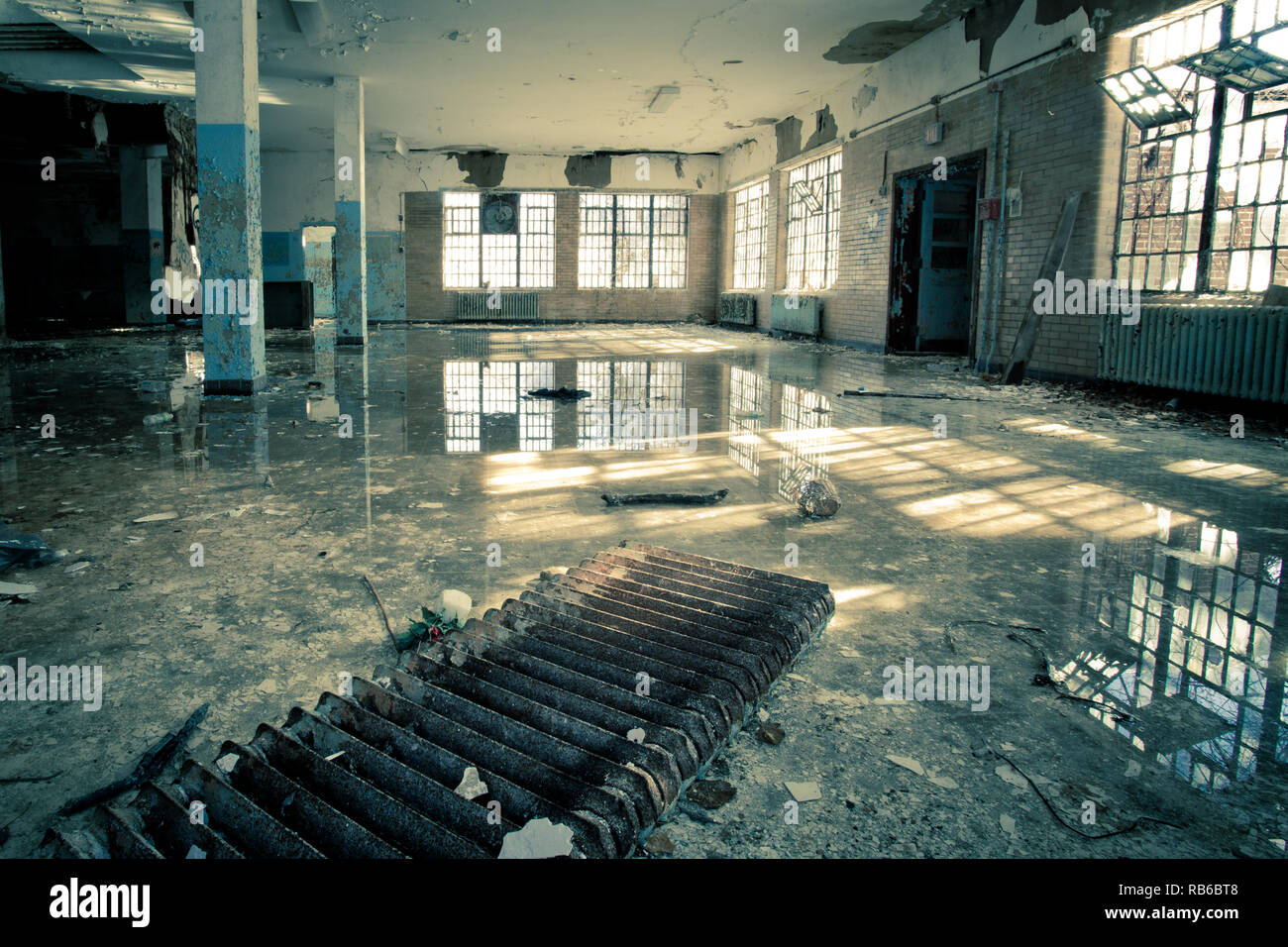 El interior del abandonado hospital psiquiátrico con ventanas rotas y las inundaciones de agua en el suelo Foto de stock