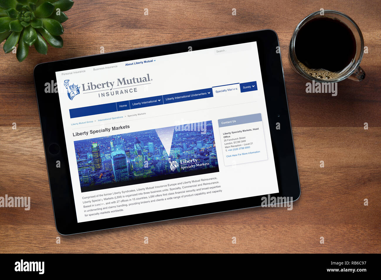 El sitio web de Liberty Mutual Insurance es visto en un iPad descansando sobre una tabla de madera (uso Editorial solamente). Foto de stock