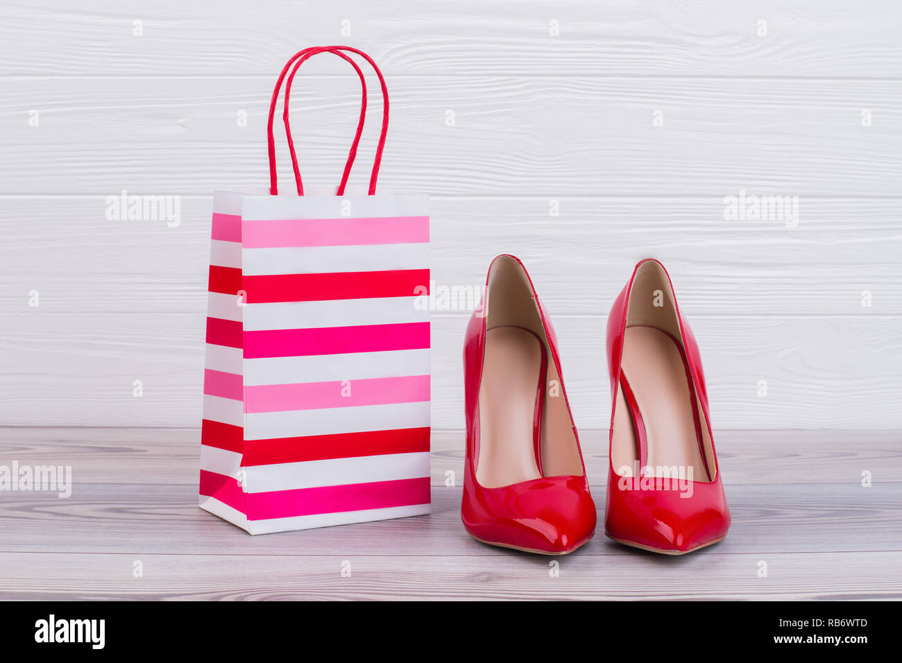 Stilettos rojo y bolsa de regalo de papel. Hembra de lujo high heels y papel shopping bag de imagen horizontal. Forma de hacer mujer feliz. Foto de stock