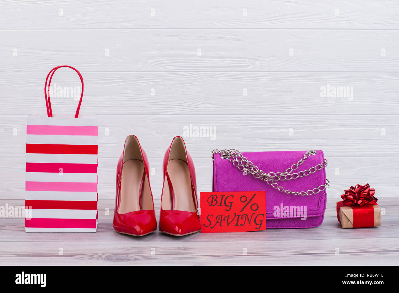 Accesorios femeninos y la tarjeta con la inscripción gran ahorro. Mujer tacones, bolso de cuero de cadena y caja de regalo sobre fondo de madera. Womens fashion venta. Foto de stock