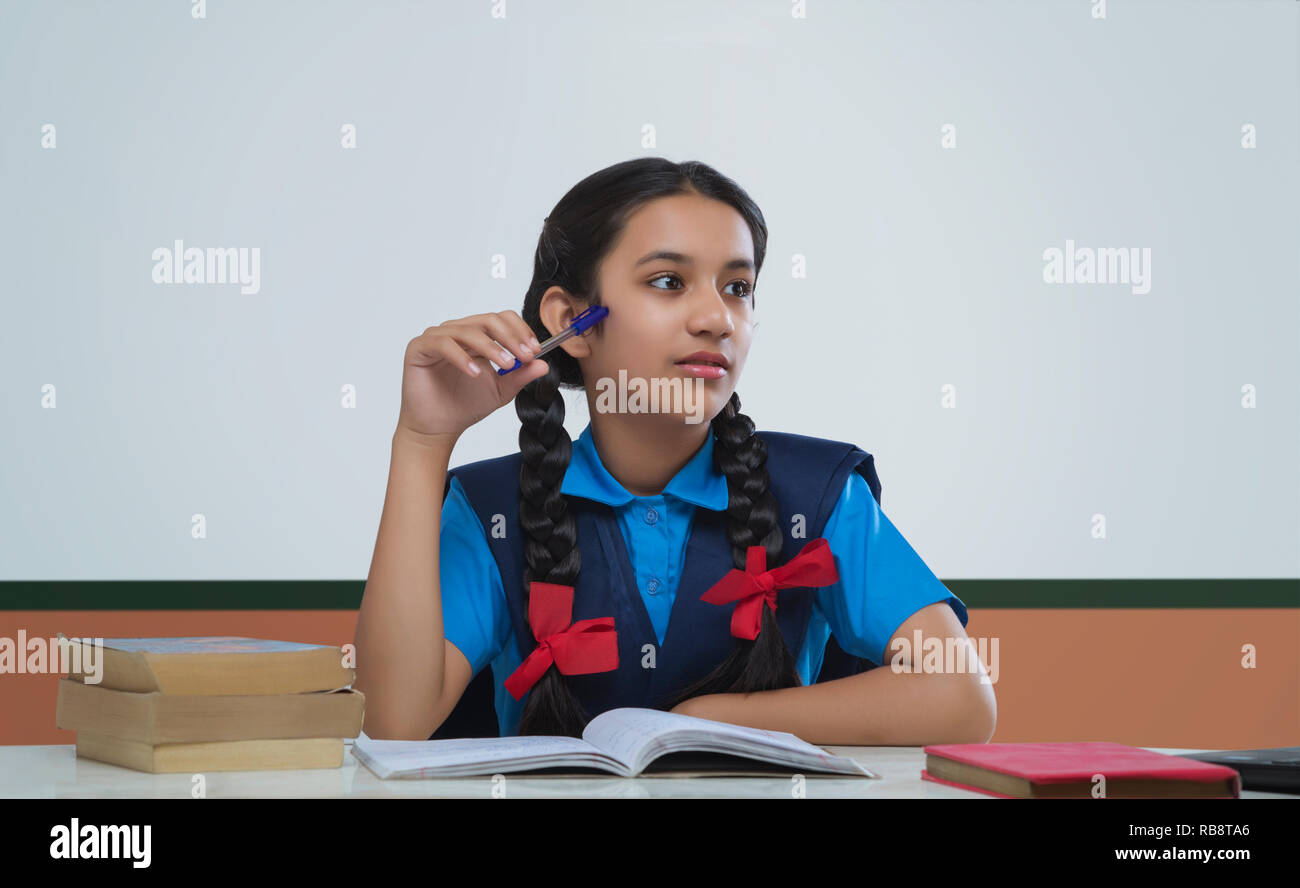 Niña de la escuela reflexiva sosteniendo pen Foto de stock