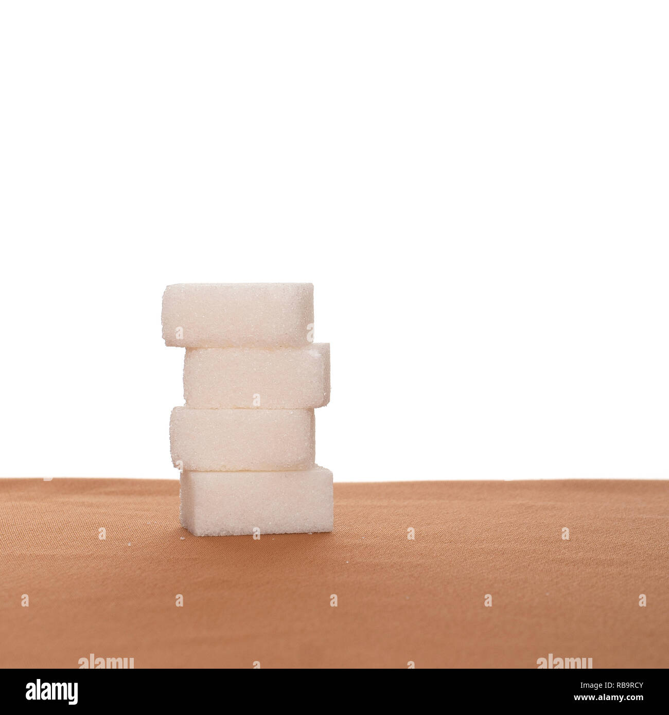 Pila de cuatro cubos de azúcar sobre tela, fondo blanco. Comer sano. Foto de stock