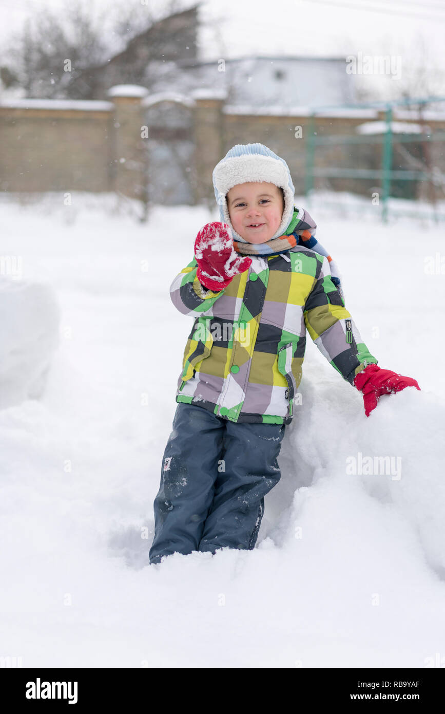 Contiene símbolo almuerzo Niño chico jugando en la nieve. Bebé jugando con nieve en invierno. Poco  niño chico de chaqueta azul y sombrero colorido atrapar los copos de nieve  en Winter Park o Fotografía de