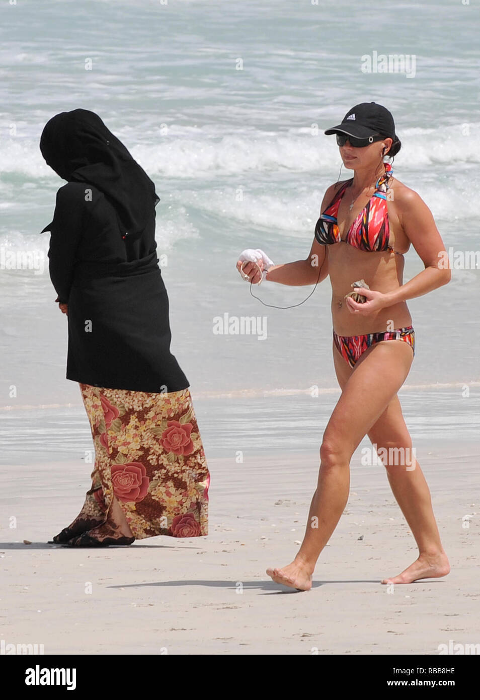 a Andrew Parsons Parsons / Medios de Comunicación. 14/05/2009. Dubai, Emiratos Árabes Unidos. mujer en bikini camina pasado un damas una abaya en una playa de Dubai como el