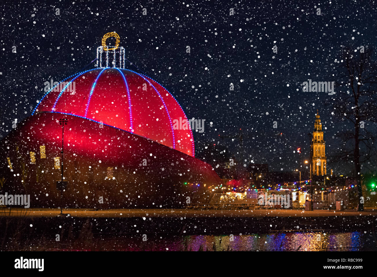 Edificio iluminado en rojo como un edificio por la noche de navidad con nieve en Groninga. Foto de stock