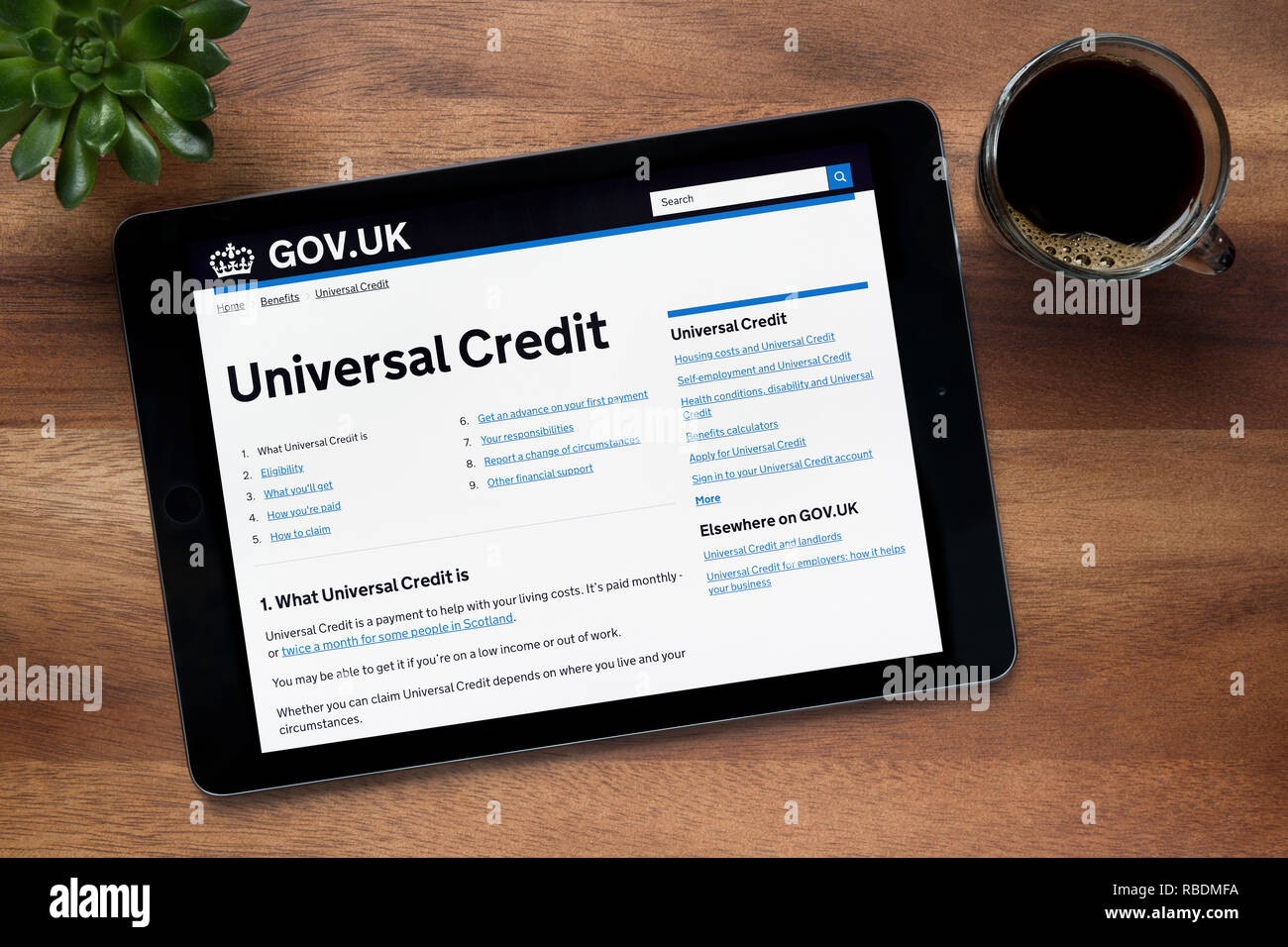 La Sección de Crédito universal de la gov.uk sitio web es visto en un iPad, descansando sobre una tabla de madera (uso Editorial solamente). Foto de stock