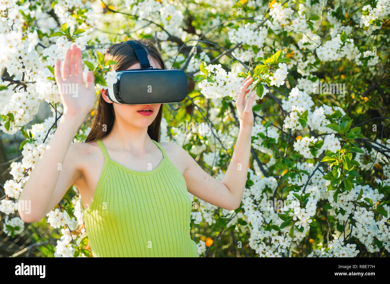 Experiencia de VR. Señorita llevar gafas vr en primavera la naturaleza. Chica guapa en casco de realidad virtual. Cute girl play en spring garden. Innovadora tecnología de VR. Simulación Virtual de la tecnología Foto de stock